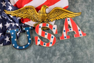 Amerikan bayrağının arkaplanında bir kartal amblemi ile süslenmiş Amerikan harfleri.
