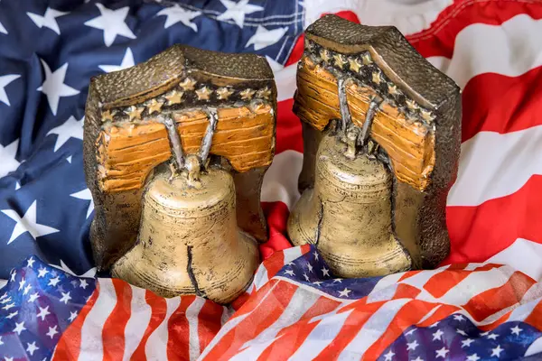 Özgürlük çanları bir Amerikan bayrağına karşı sergileniyor, kutlamalar sırasında vatanseverliği sembolize ediyor, ulusal tatiller.