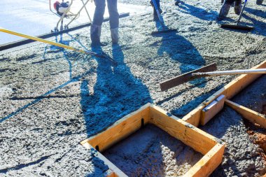 İnşaat işçileri beton döküyor. Çalışma günlerinde temel için ahşap çerçeveler yapıyorlar.
