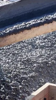 İşçiler inşaat alanındaki ahşap formlara taze beton dökerler.