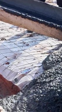 İşçiler inşaat alanında ahşap formları betonla dolduruyorlar.