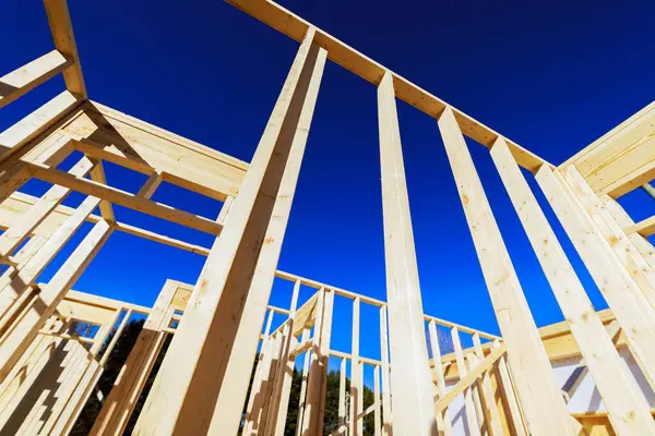 Binanın ahşap kirişleri devam eden inşaatta açık mavi gökyüzüne doğru yükseliyor.