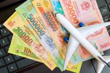 Vietnam dong banknotları nakit para notları dizüstü bilgisayar üzerinde model uçak seyahat planı önerir.