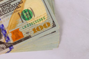 Nakit para biriminin karmaşık tasarımlarını vurgulayan 100 dolarlık banknotlar yığını.