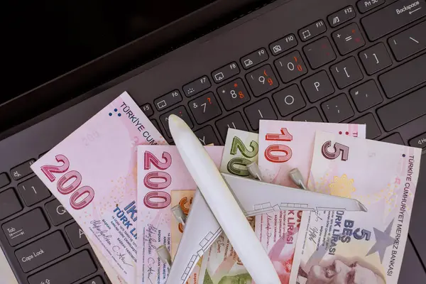 Lira, Türkiye 'de seyahat planlama finans bütçesi öneren nakit para banknotları model uçağın dizüstü bilgisayarda dinlendiğini belirtiyor.