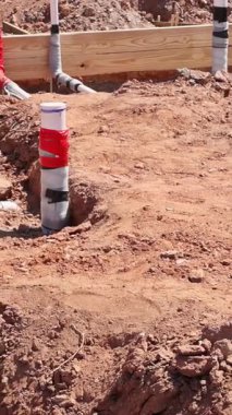 İşçiler iş günü yeni kazılmış şantiyeye atık su tesisatı döşüyorlar.