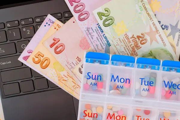 Çeşitli değerler Türk lira banknotları ve ilaç organizatörü, finansmanın sağlık ihtiyaçlarıyla dengelenmesinin önemini yansıtıyor.