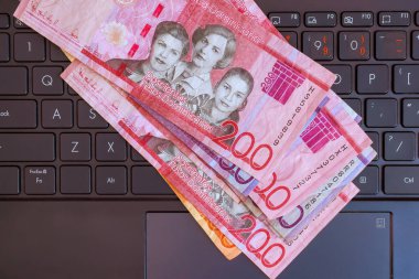 Dominik pezosu, modern çalışma ortamında dizüstü bilgisayarın klavyesine para harmanlama teknolojisi sergiliyor..