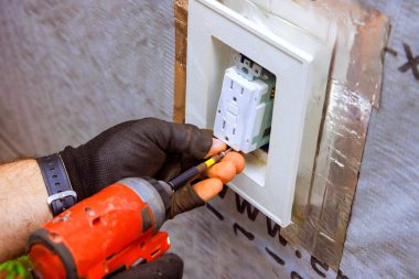 Bir elektrikçi eve elektrik prizi kurarak güvenli ve verimli elektrik tesisatı kuruyor..