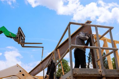 İşçi inşaat alanındaki metal kirişleri kaynaklıyor, yoğun bir şekilde iş gününün altındaki göreve odaklanıyor