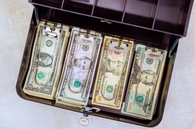 Toplanan Amerikan dolarlarının toplanması güvenli metal çantada düzenlenerek mali yönetim vurgulanır.
