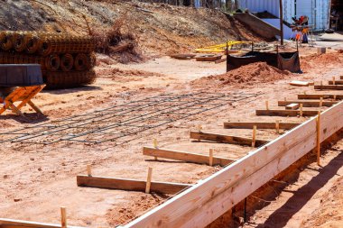 İnşaat işçileri, çalışma gününün altındaki yerleşim bölgesinde beton levha için ahşap inşaat demiri kurdular.