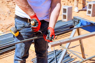 İnşaat işçisi inşaat sahasında eldiven giyerken metal inşaat demiri kesiklerini kavradı.