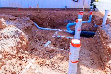 İşçiler iş saatlerinde banliyö şantiyesinde yeni tesisat hatları için hendek kazıyorlar.