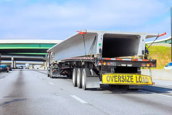 Otobanda üst geçitlerden beton levhalar taşıyan büyük bir kamyon.