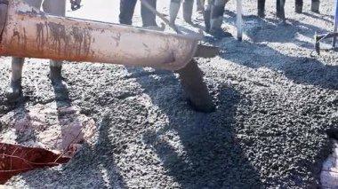 İnşaat işçileri çalışma gününde temel döşemeleri hazırlarken beton karışımı döküyorlar..