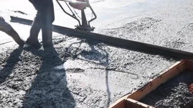 İşçiler inşaat alanında dökülen çimentoyu düzeltmek için beton seviyelendirme aracı kullanıyorlar.