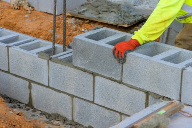 İşçi inşaat alanında inşaat yaparken beton blokları dikkatlice yerleştiriyor.