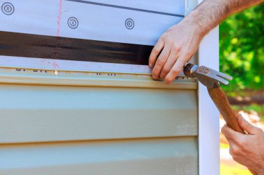 Craftsman is skillfully applying PVC vinyl siding for house, highlighting their attention to detail