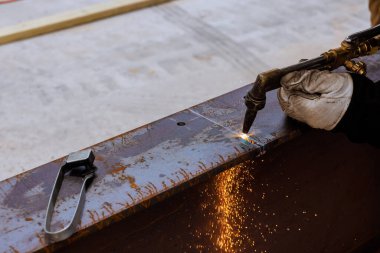 İşçi kaynak makinesini kullanarak metali dikkatlice kesiyor, yoğun endüstriyel mekanlarda iş günü altında kıvılcımlar yaratıyor.