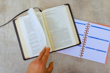 24 April 2025 Washington DC US Hand flips page in Bible, Holy book next to planner, emphasizing focus on learning weekly planning.