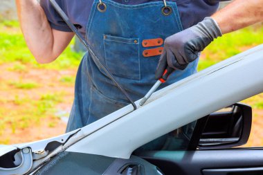 İşçi arabanın iç kısımları üzerinde çalışıyor. Buna garajın ön camında silikon tamiri de dahil..