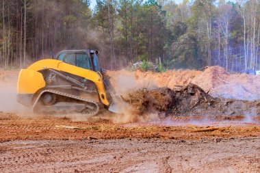 Buldozer, ormanlık alandaki enkazı ve inşaat sahasında yükselen toz dumanını temizlemek için özenle çalışıyor.