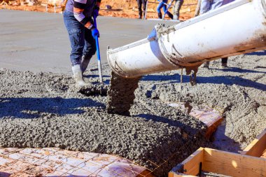İnşaat işçileri zemine taze beton dökerek hazırlanan koşulları sağlamlaştırıyor..