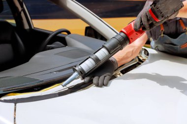 Skilled technician works on removing windshield with specialized tools in auto repair environment.