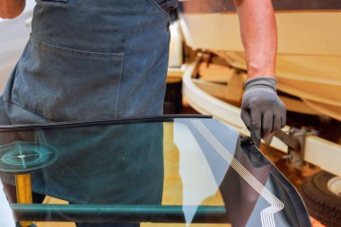 İşçi oto tamirhanesinde düzgün hava geçirmezlik için arabanın ön camına mühür takar