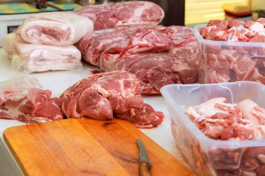 Kasap dükkanının ahşap yüzeyinde çeşitli domuz kesimleri düzenlenerek taze ürünlerin hazırlanması vurgulanır..