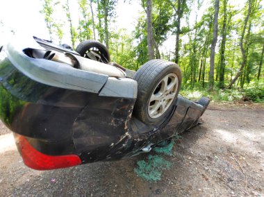 Hasarlı araç ağaçlık toprak yolda yan yatmış ve araç çarpmış.