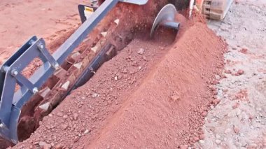 Kazıcı inşaat sahasında faaliyet gösteriyor, inşaat faaliyetlerine hazırlanırken toprakta çukur kazıyor.