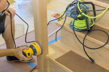 Zanaatkar, ev tadilatı sırasında tahta korkuluklarda zımpara kullanıyor..