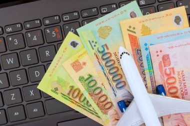 .Çeşitli Vietnam dong banknotları dizüstü bilgisayara yerleştirilmiş minyatür uçak, seyahat planının finansal yönlerini sembolize ediyor
