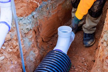 İşçiler kanalizasyon borularını birbirine bağlayarak, iş günü altındaki inşaat sahasında düzgün bir kurulum sağlıyorlar