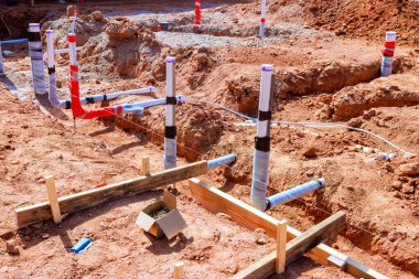 İşçiler iş günü yeni kazılmış şantiyeye atık su tesisatı döşüyorlar.