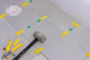 Ev tadilatında fayansların döşenmesi için yere uzay araçlarıyla gri fayanslar yerleştiriliyor