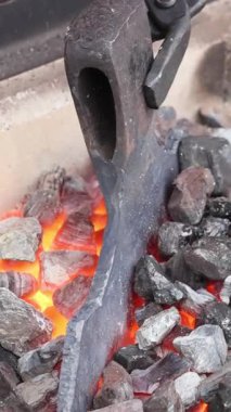 Usta demirci, balta yaparken sıcak metali manipüle etmek için maşa kullanır.