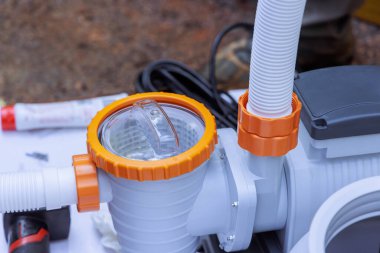 İşçi açık hava ortamında havuz pompası monte eder, ayrıntılara dikkat eder.