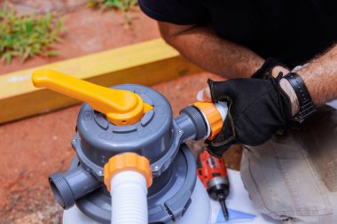 Ev arka bahçesindeki havuz filtresini bağlama üzerine bireysel çalışmalar, kullanılan aletleri gösterir.