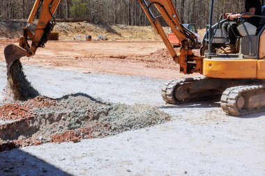 Bir kazıcı inşaat alanındaki çakıl taşlarını iş günü ile birlikte taşır