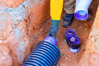 İşçiler kanalizasyon kanalizasyon borularını inşaat alanına ve su tesisatına dikkatlice yerleştiriyor.