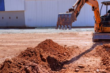 Kazıcı, inşaat alanı endüstriyel makinelerinde büyük bir çukur kazmak için özenle çalışıyor.