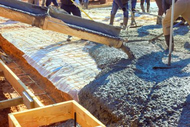 İnşaat işçileri ustalıkla zemine beton dökerek temel oluşturuyorlar.