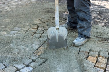 İnşaat işçisi inşaat alanındaki çakıl taşlarına kürek serpmek için kürek kullanıyor.