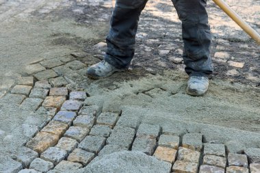 İnşaat işçisi şehrin işlek sokaklarındaki çakılların arasına kaldırım taşlarını dikkatlice yerleştirdi..
