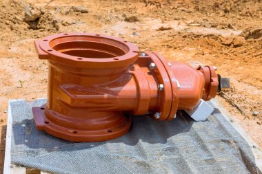 Büyük, turuncu borulu yangın tesisatı, inşaat alanındaki ahşap platforma kurulmayı bekliyor.