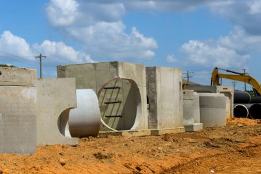 İşçiler, çalışma gününde drenaj inşaat projesi için somut elementler düzenlemeye hazırlanıyorlar