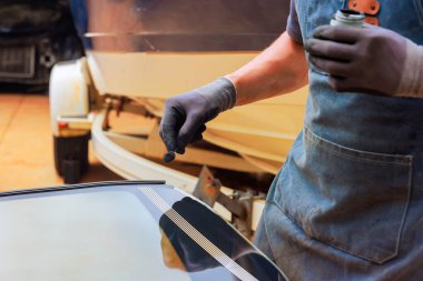 İşçi, kurulum sırasında garajdaki arabaya dolgu macunu uygular.